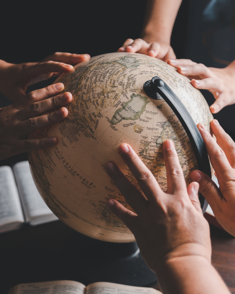 Plusieurs mains entourent un globe terrestre pendant un temps de prière